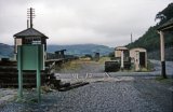 This is part of a survey of Penmaenpool station comprising 56 shots all taken c1970, after the track had been lifted but before any of the major structures had been demolished. Today, the signal box remains as an RSPB observation and information post, whilst the station building has been rendered, painted white and is now a private dwelling. All other structures were demolished circa 1976, whilst the original bracket signal seen in some of these photos adjacent to the George Hotel has been replaced by a more modern tubular post signal. This survey, including many detail shots, would be most useful for anyone wishing to make a model of this station. The GWR line from Ruabon and Bala Junction made an end on junction with the Cambrian Railways Dolgelley Branch at Dolgelley but the Cambrian sited their engine shed here at Penmaenpool.